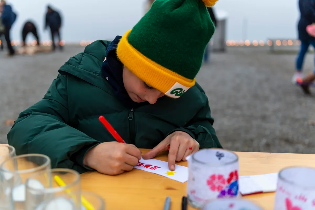 Ein Kind malt an einem Tisch, dahinter der Pfäffikersee.